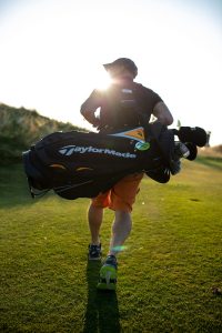 Un homme portant un sac d'équipement de golf."
