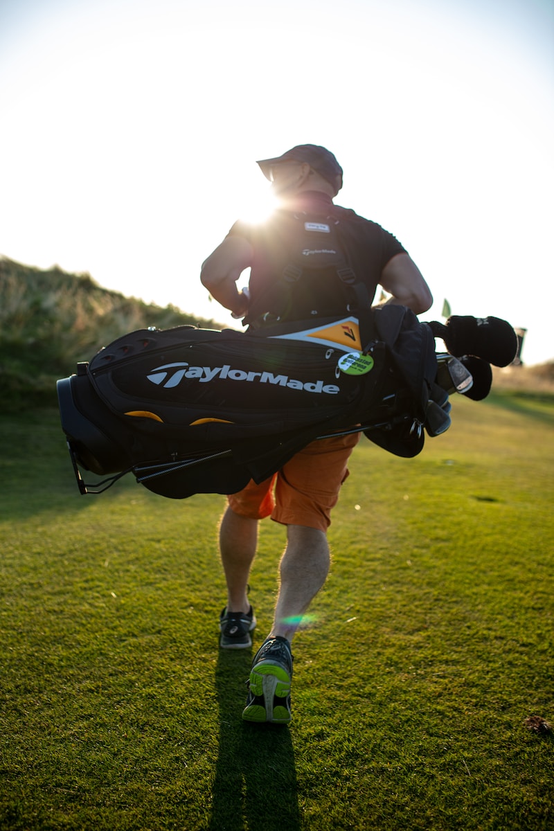Un homme portant un sac d'équipement de golf."